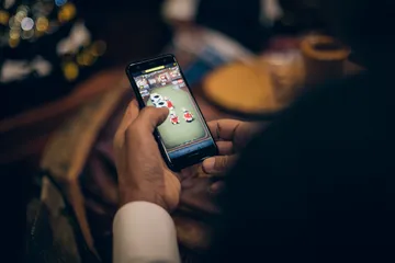 A man celebrating a winning moment on his laptop while gaming symbols float around him, capturing the excitement of 88DF games.